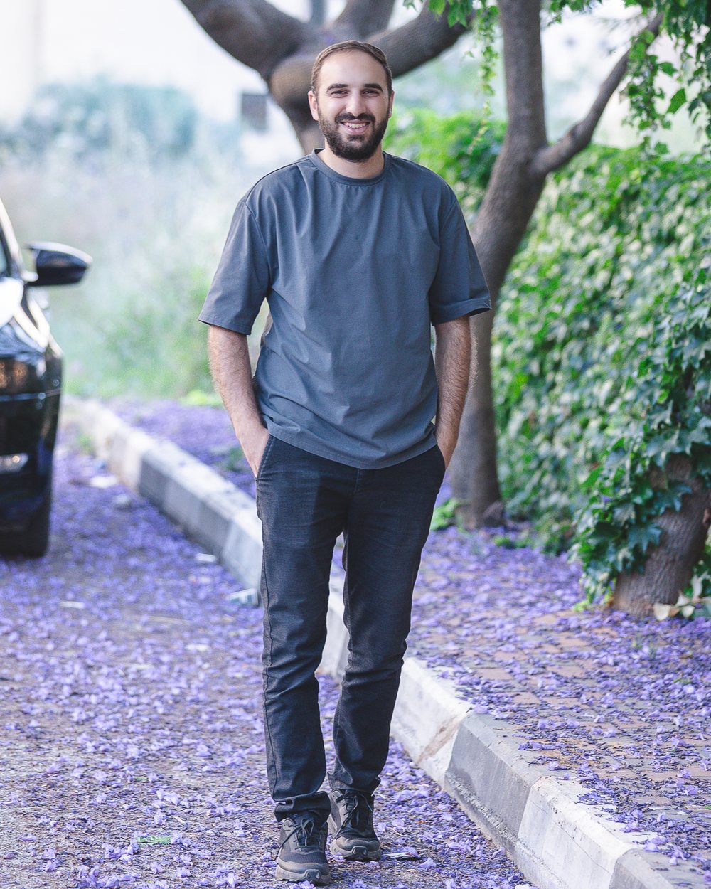 Mohammad Juber walking on a street covered in jacaranda petals