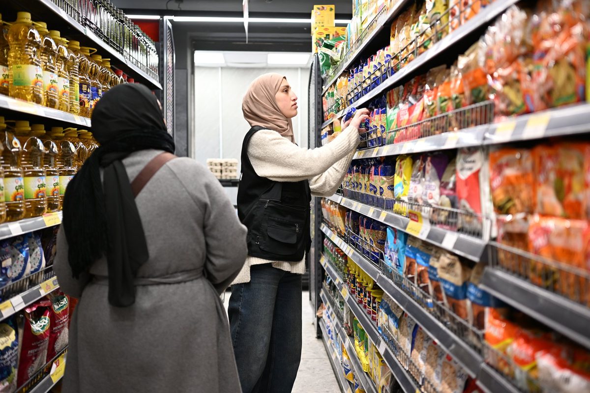 A staff member helps a woman pick items from the shelves