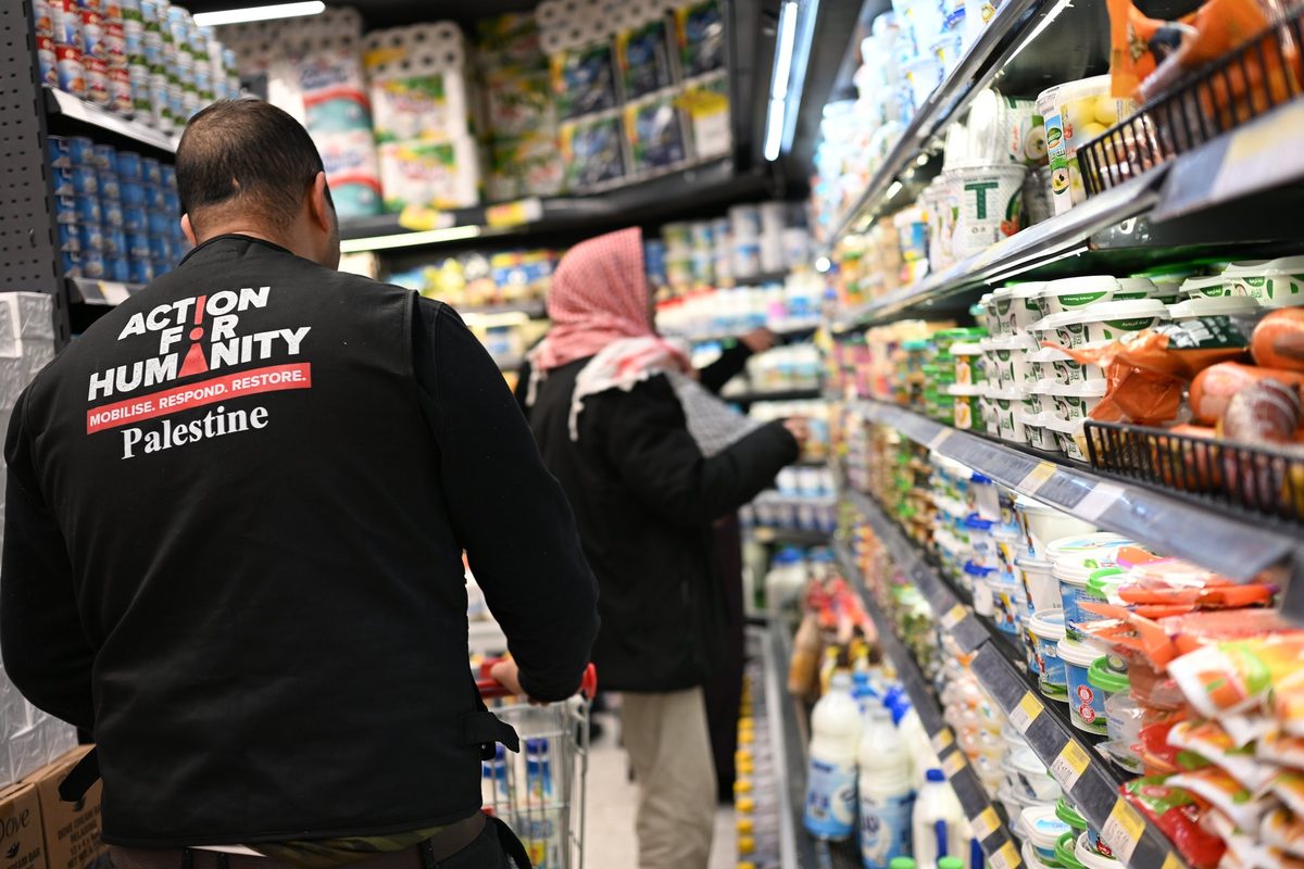 An aid worker in an Action for Humanity vest in a supermarket aisle