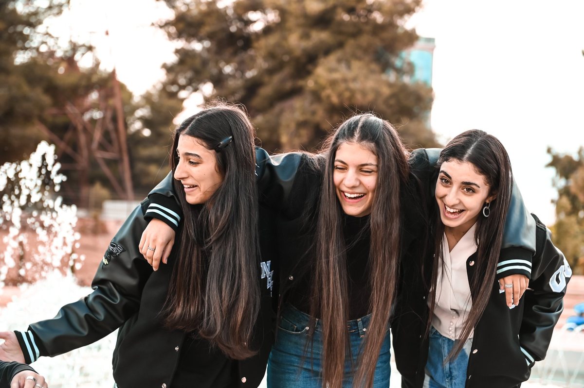 Three friends laughing in matching varsity jackets