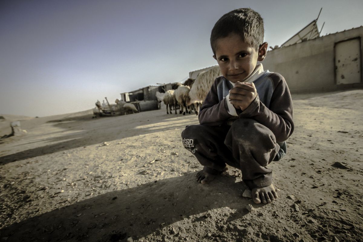 A boy crouching in a desert village