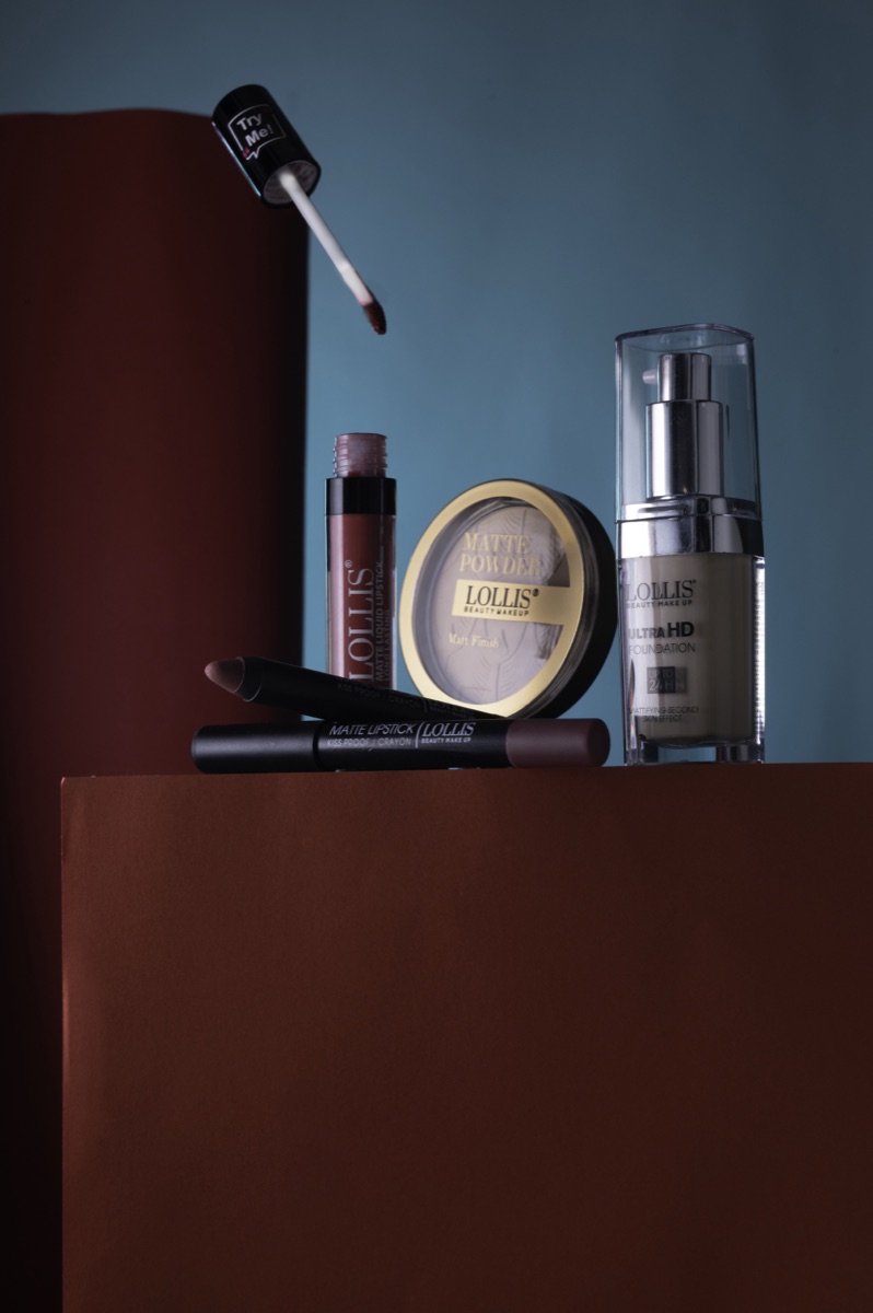 A set of LOLLIS lipsticks, powder and foundation on rust-colored blocks