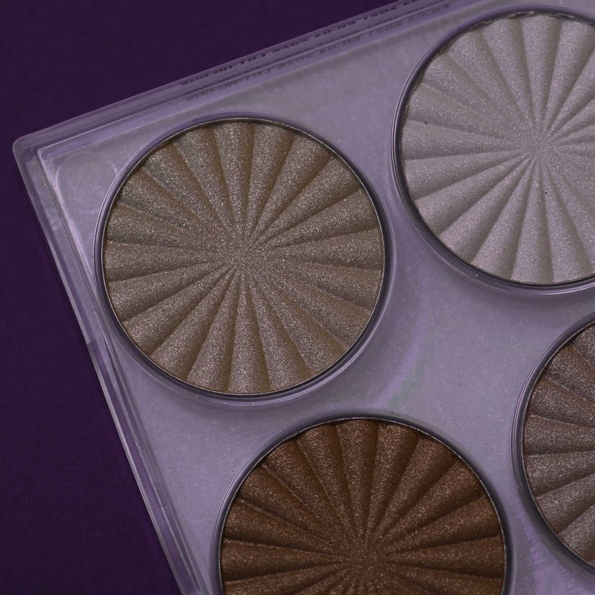 A close-up of LOLLIS highlighter pans on purple