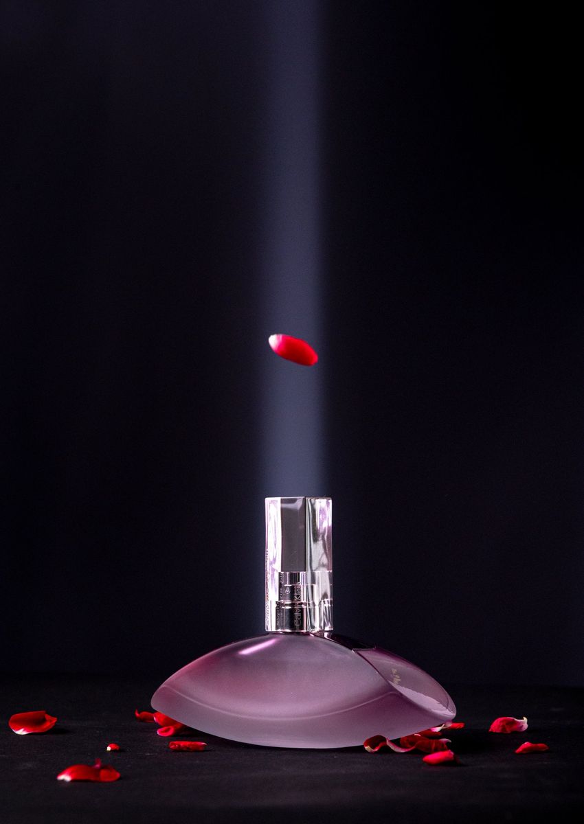 A perfume bottle with rose petals