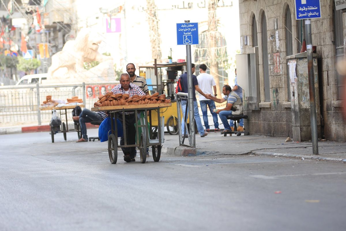 A vendor pushing a cart of bread