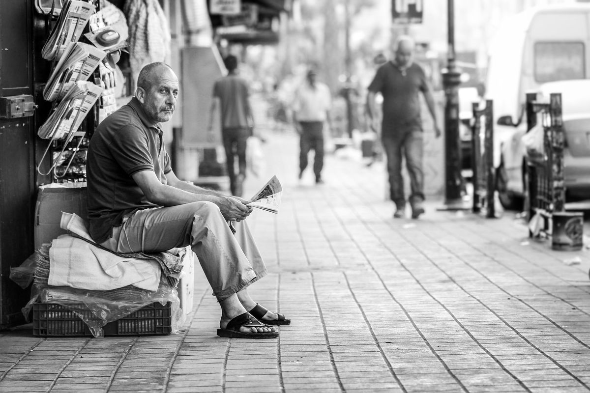 A man sitting on a pavement, black and white