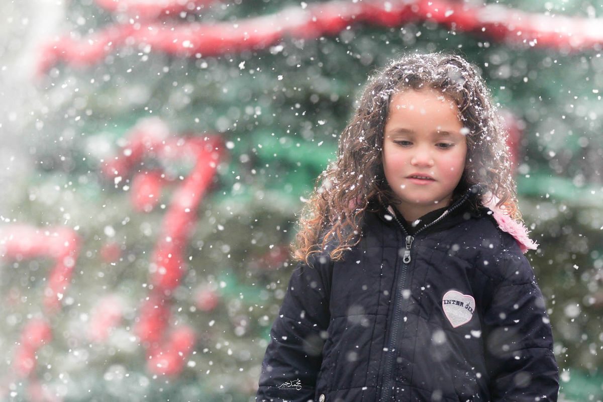 The curly-haired girl looking down in the snow