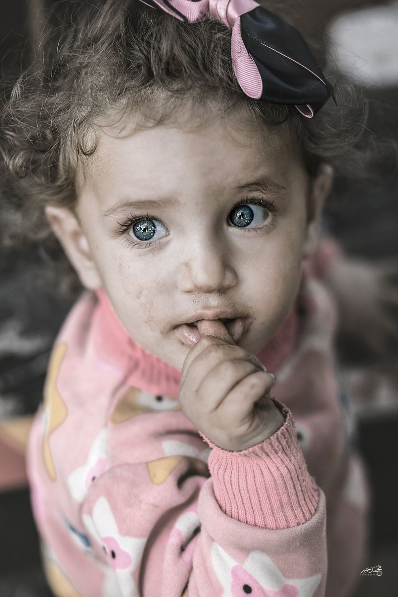 A little girl with blue eyes, finger to her lips