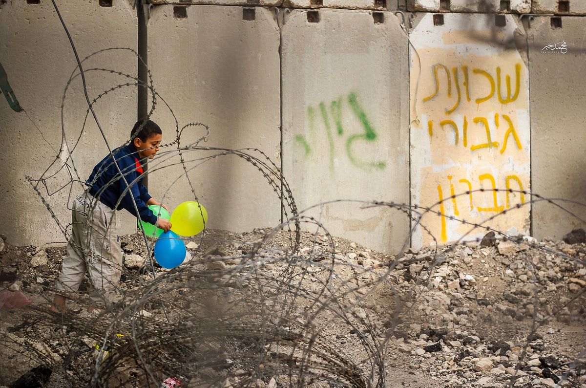 A boy with balloons by the separation wall