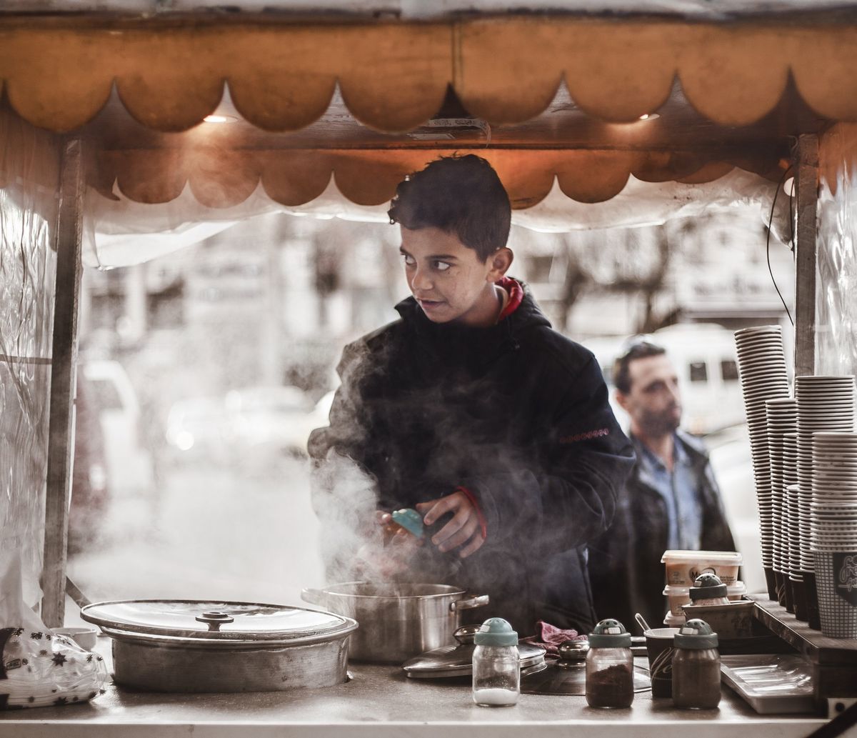 A boy at a steaming street-food stall