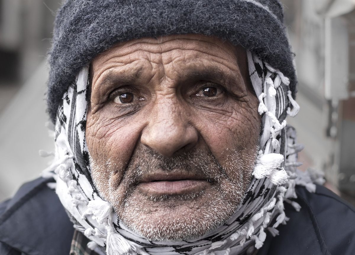 An old man in a wool hat and keffiyeh