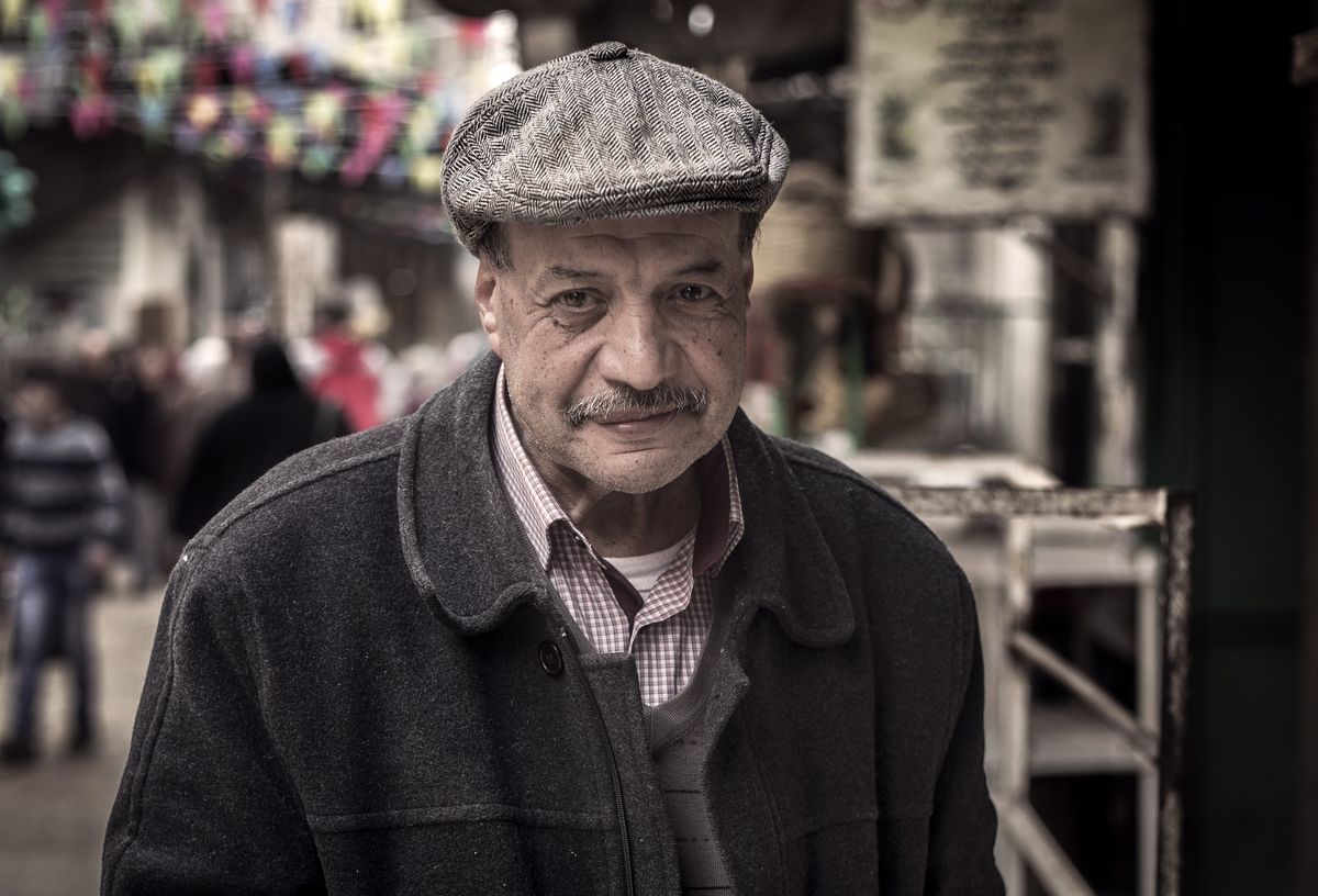 A man in a flat cap in a market