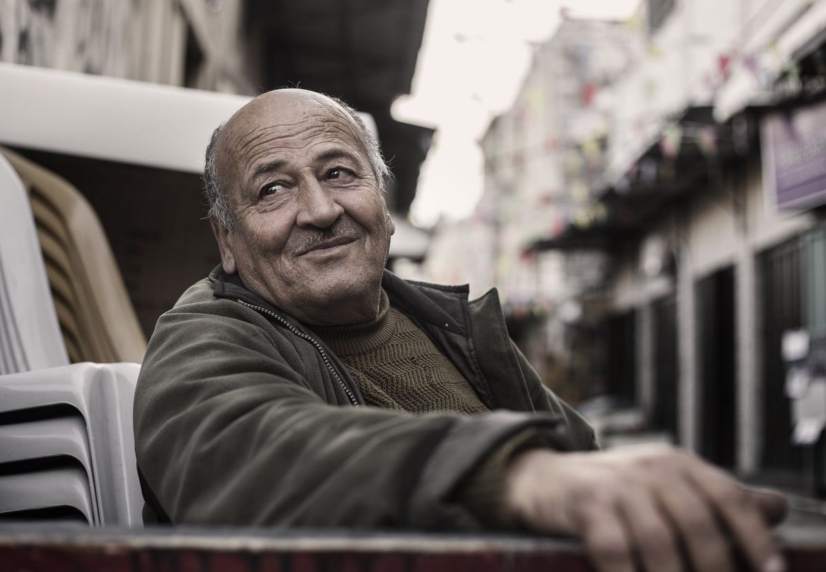 An old man smiling in an old-city street