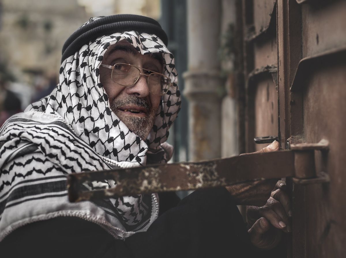 A man in a keffiyeh at a shop door