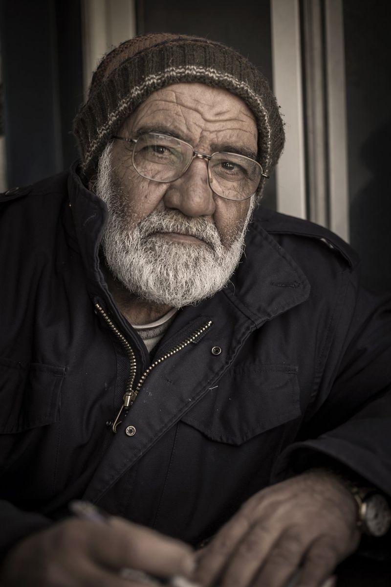 An old man with a white beard in a wool hat