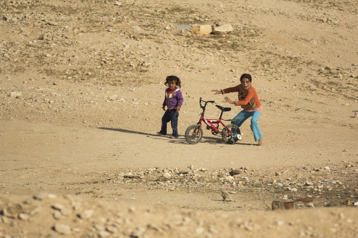 Two children with a bike on a dusty hill