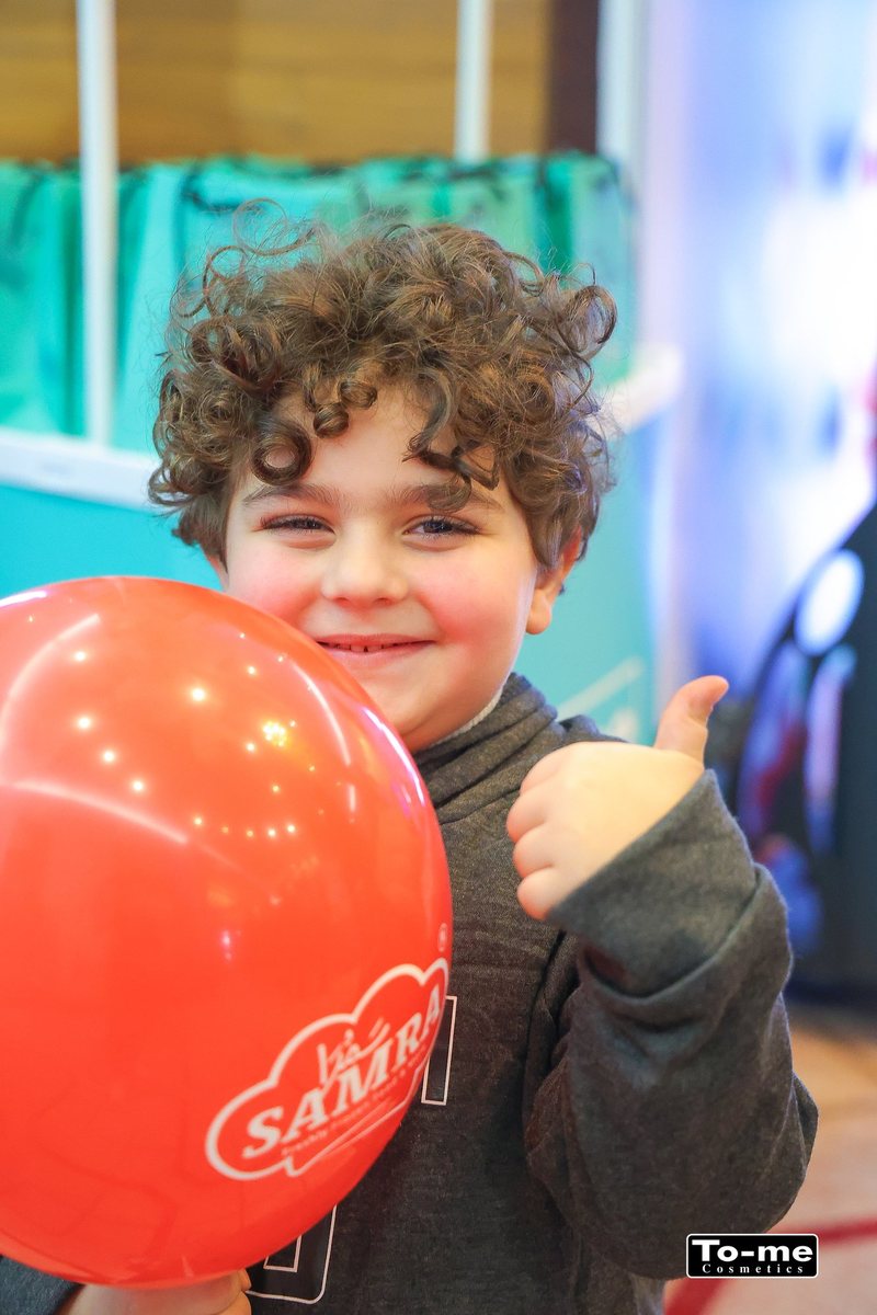 A boy with a balloon gives a thumbs up