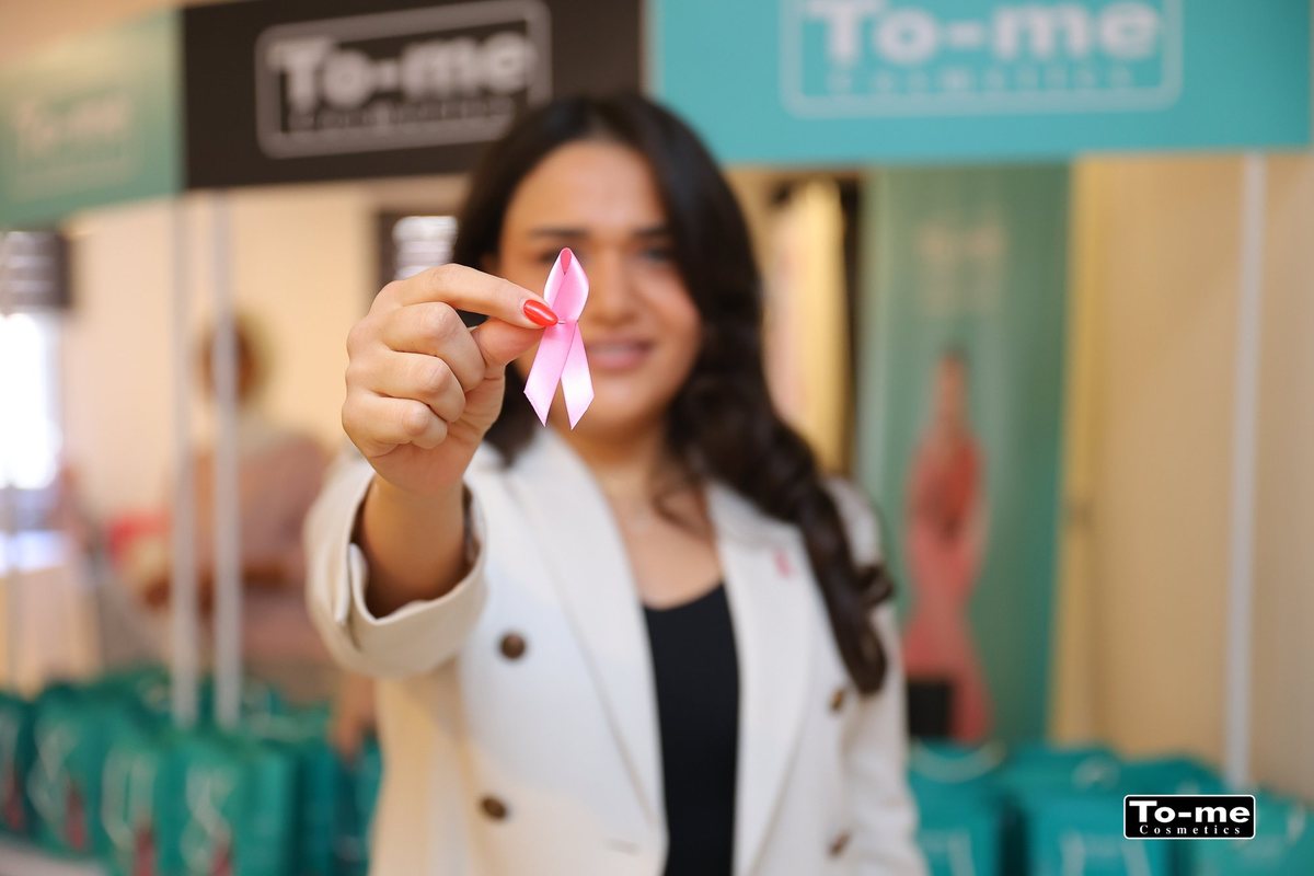 A woman holds up a pink ribbon