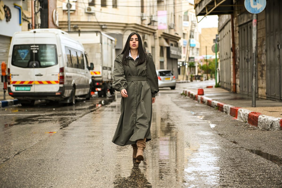 An olive-green trench coat on a rainy street