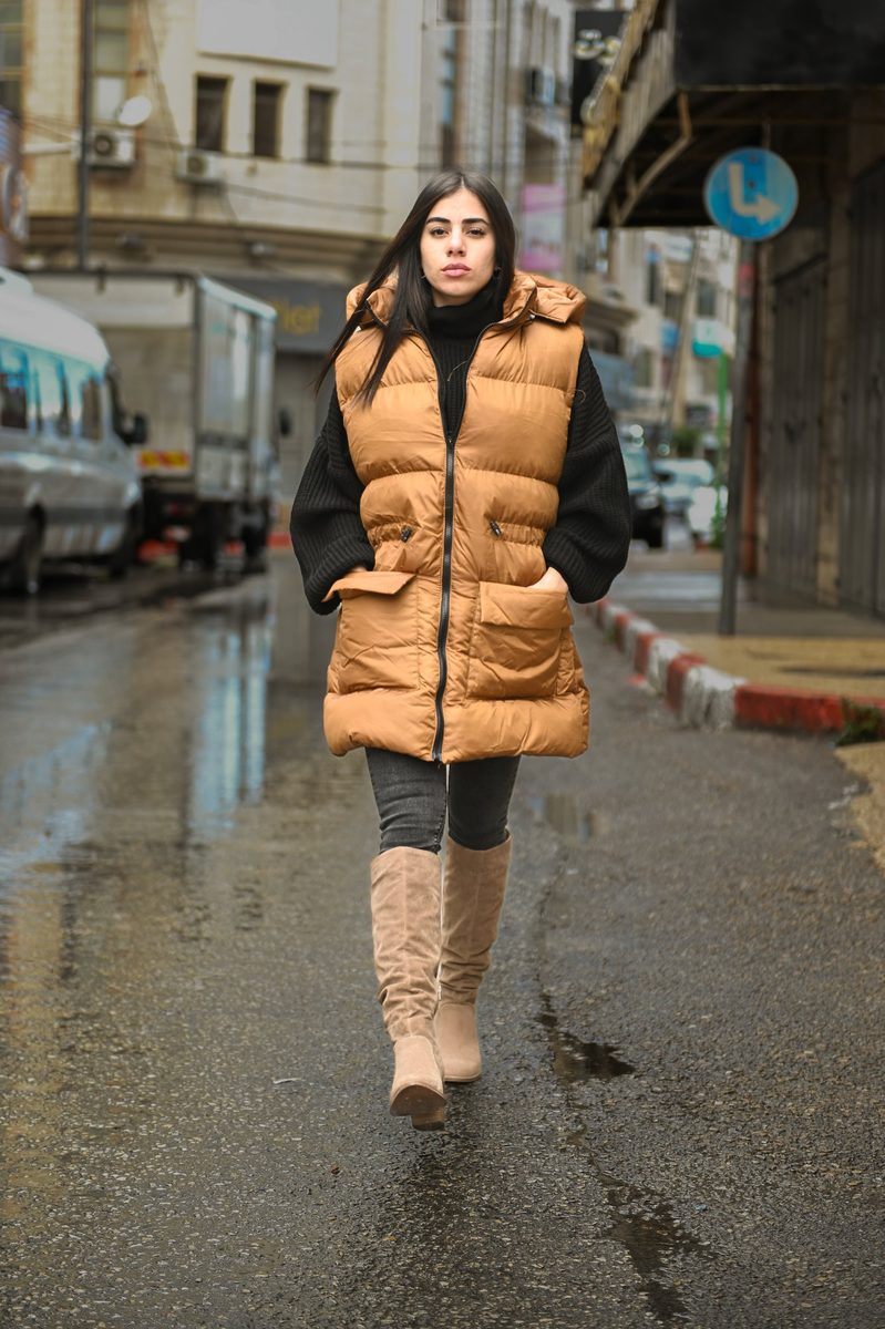 A mustard puffer vest on a rainy street