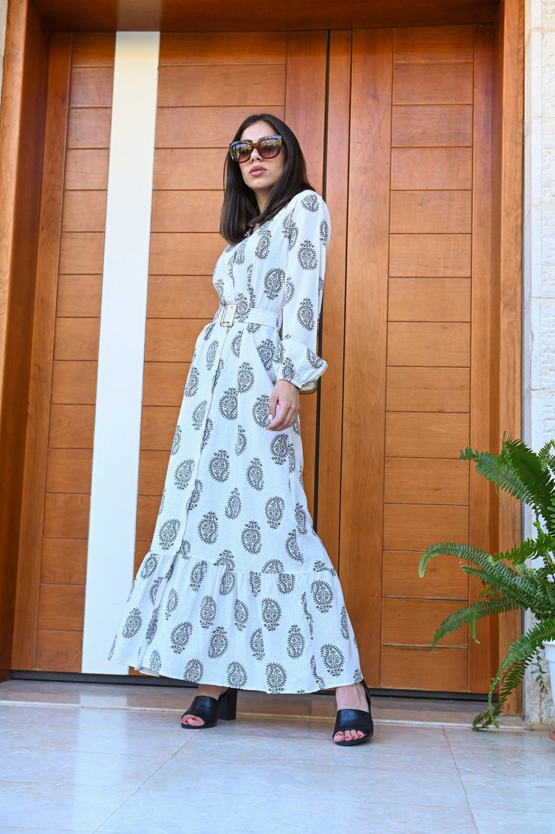 A white printed maxi dress and sunglasses at a wooden door