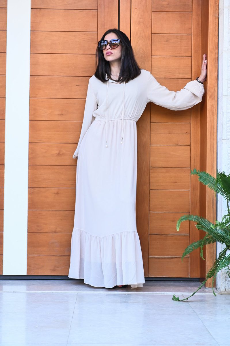 A cream ruffled maxi dress at a wooden door